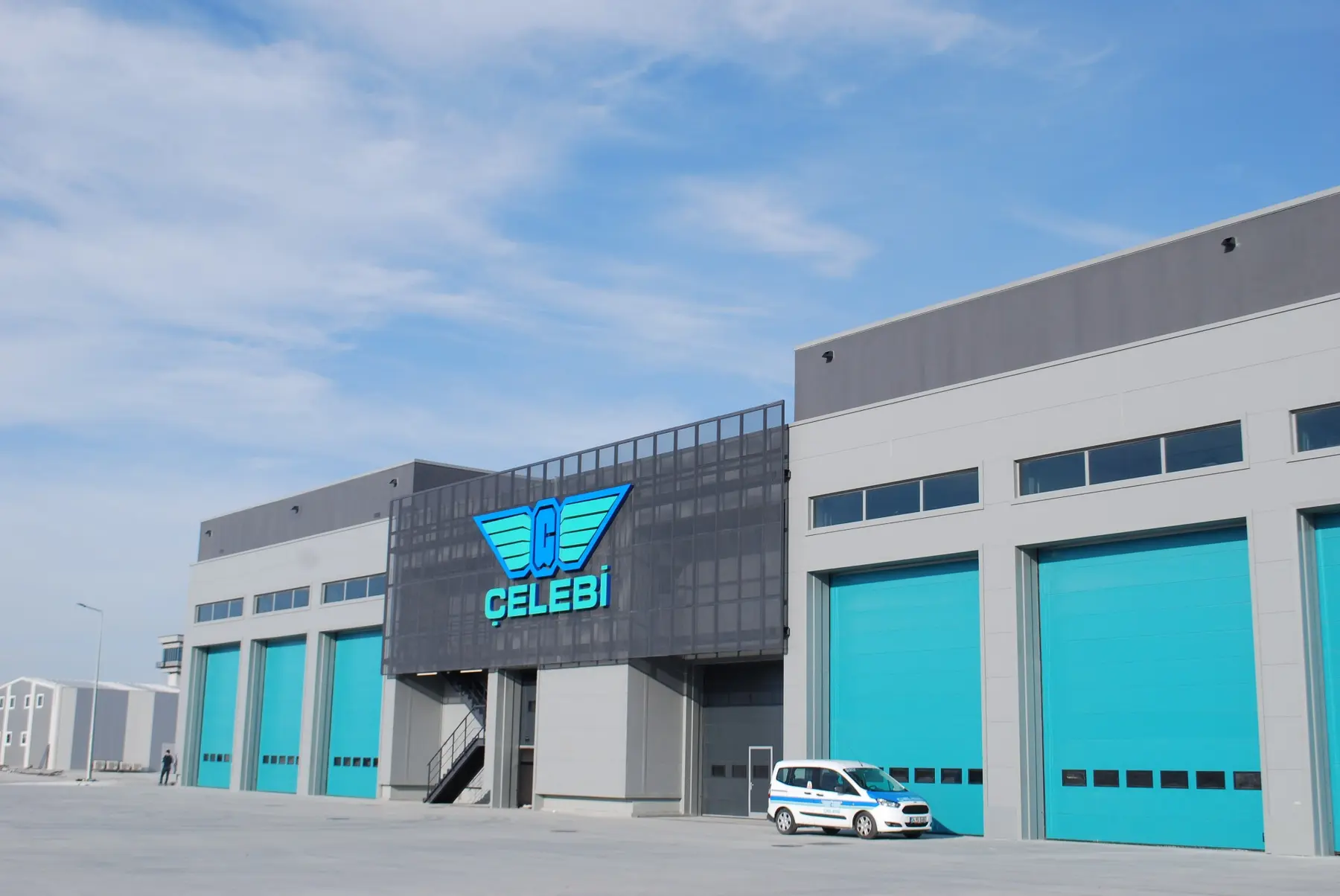 Gri ve turkuaz panellerle tamamlanmış endüstriyel yapı cephesi