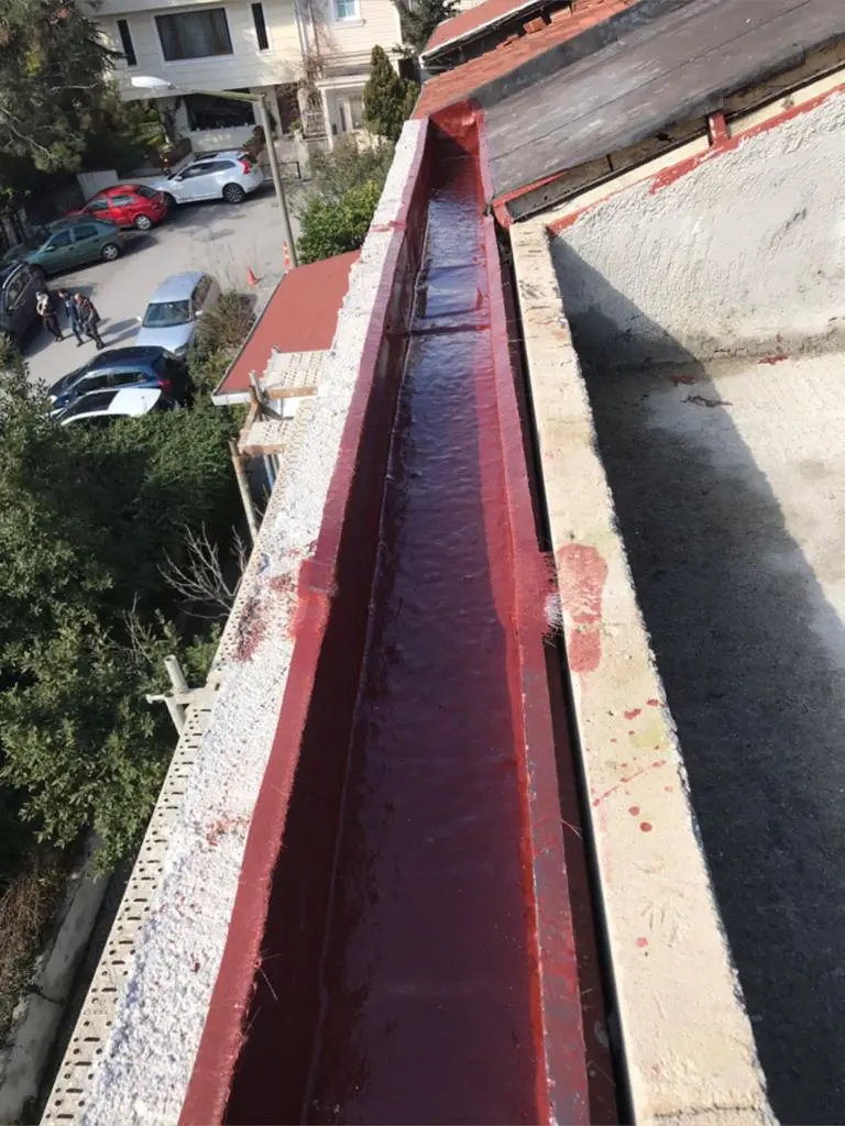 Konut çatısında kırmızı renkli sıvı yalıtım uygulanmış dere