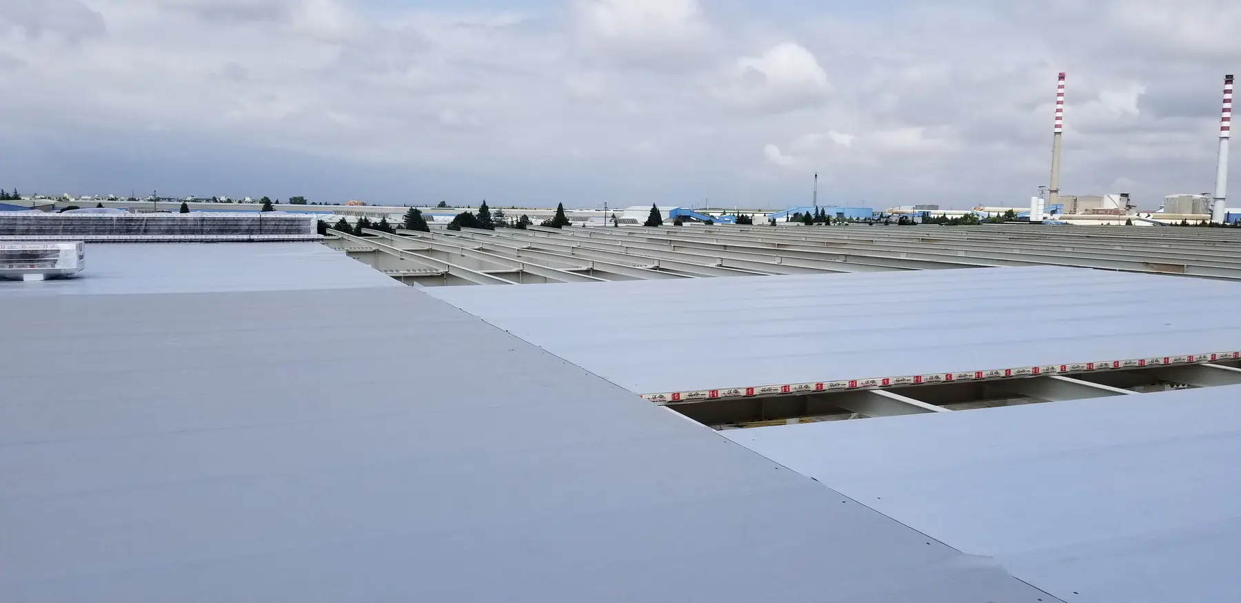 Geniş endüstriyel çatı üzerinde tamamlanmış açık renk membran uygulaması