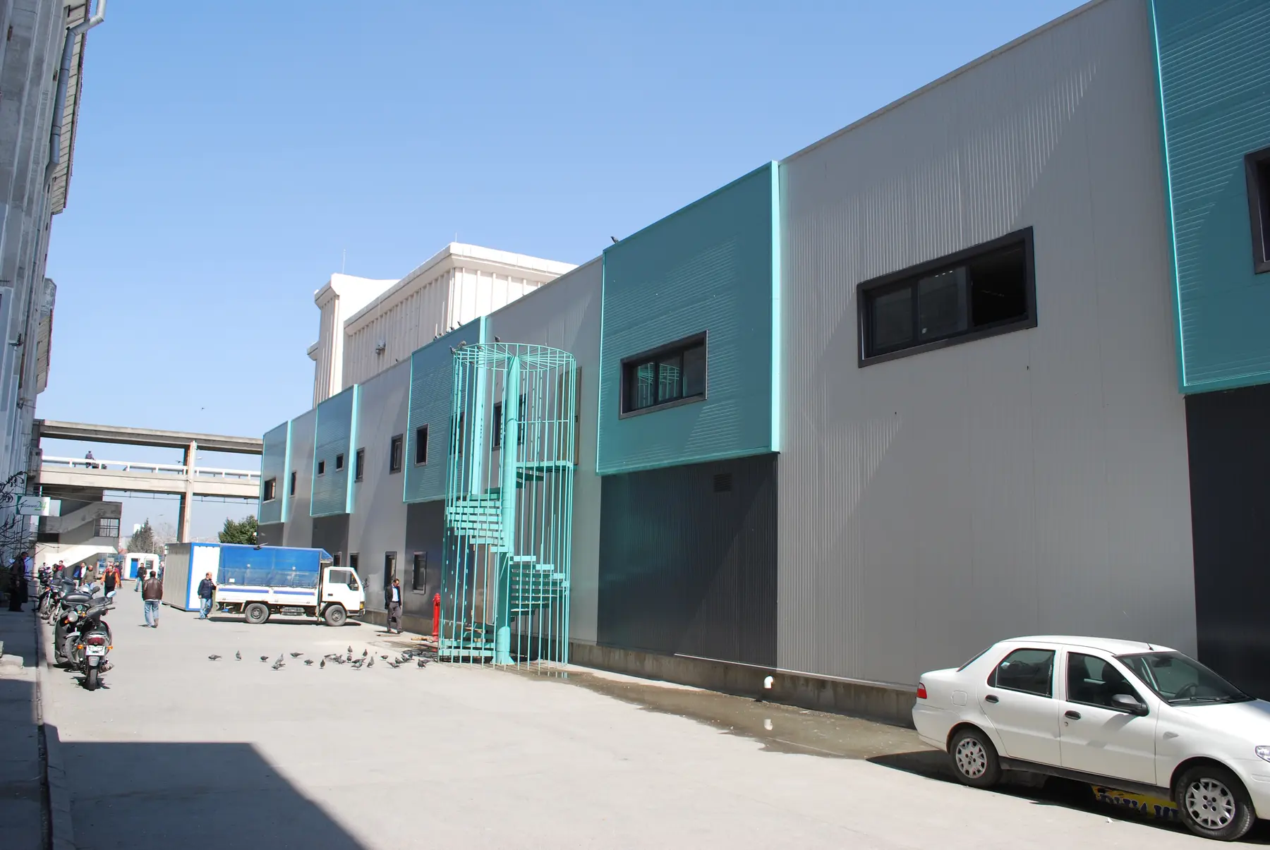 Gri panel cephe ve turkuaz detaylı endüstriyel yapı